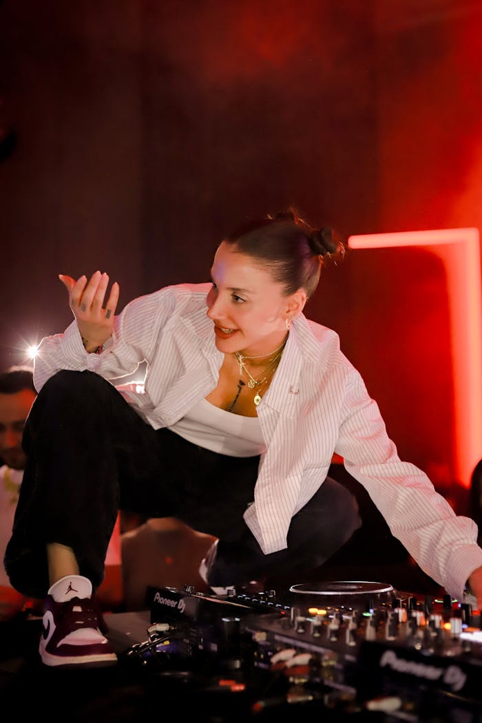 A lively DJ performing on stage at a nightclub with vibrant lighting.